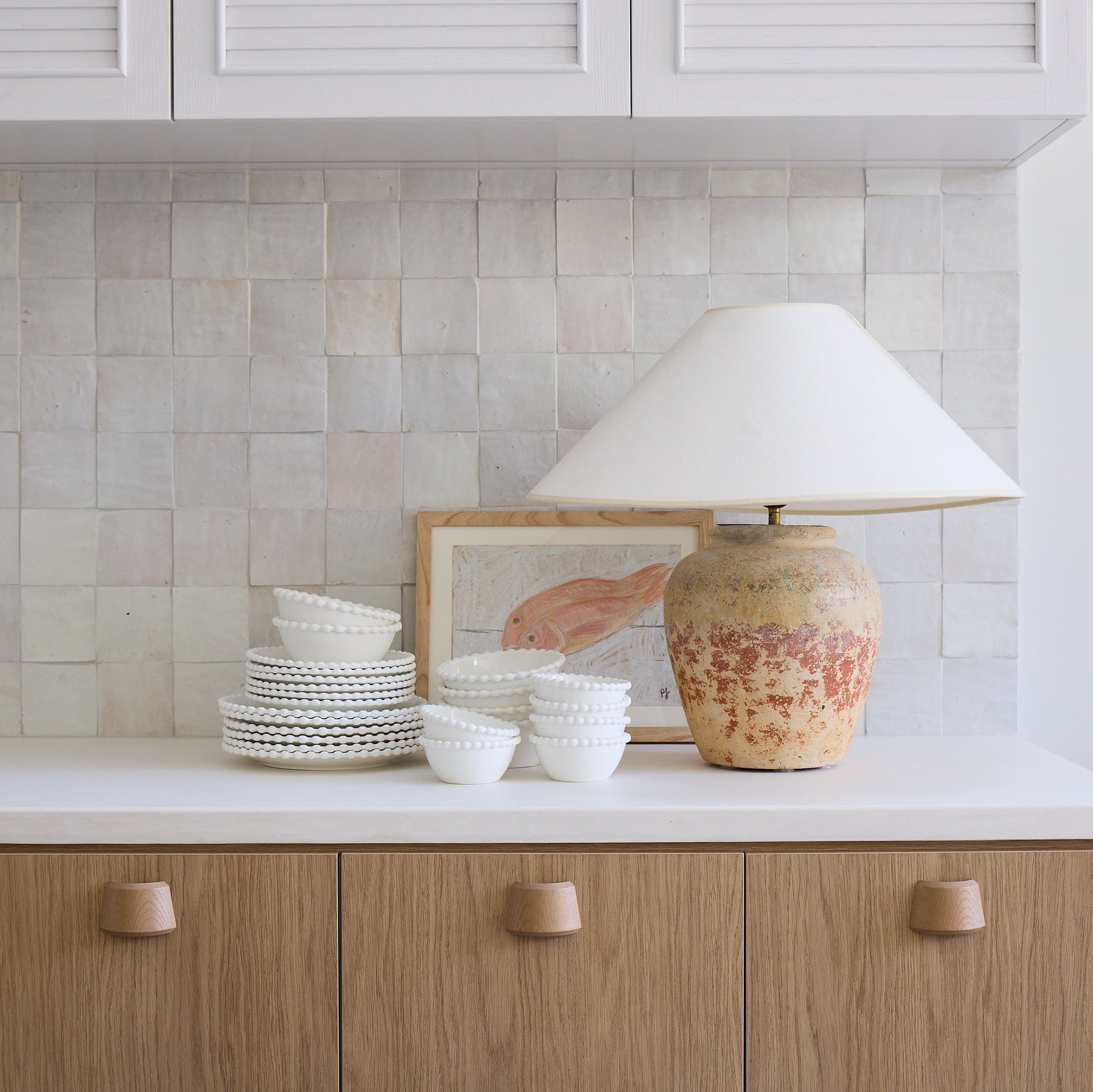 Kitchen counter with ceramic items and a lamp against a tiled wall.