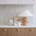 Kitchen counter with ceramic items and a lamp against a tiled wall.
