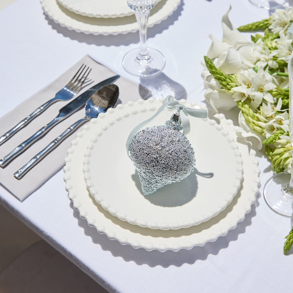 Elegant table setting with crystal glasses, silverware, and floral decorations on a white tablecloth.
