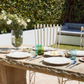 Outdoor dining setup with table, chairs, and a vase of flowers in a garden.