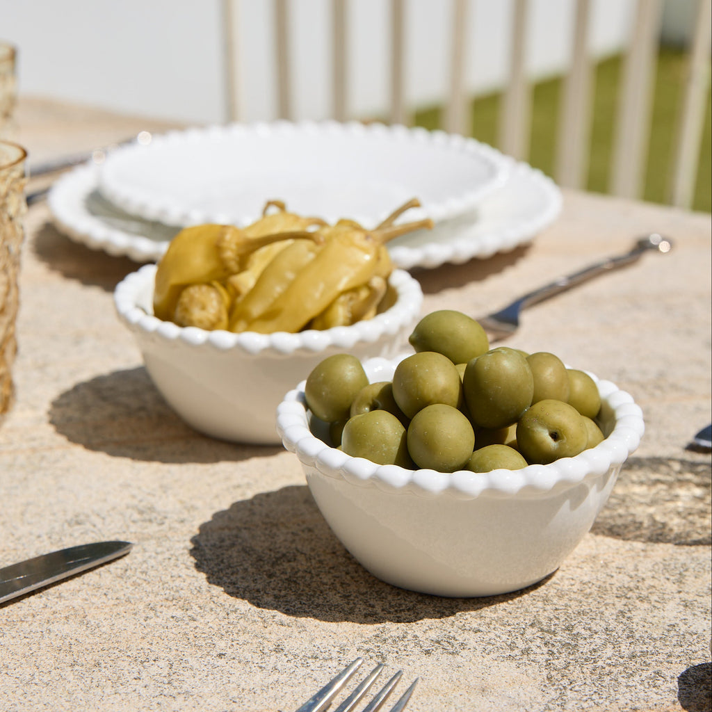 Two bowls of pickled vegetables on a table with plates and cutlery.