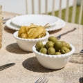 Two bowls of pickled vegetables on a table with plates and cutlery.