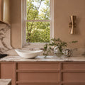 Modern kitchen with marble countertop, sink, and window view of greenery.