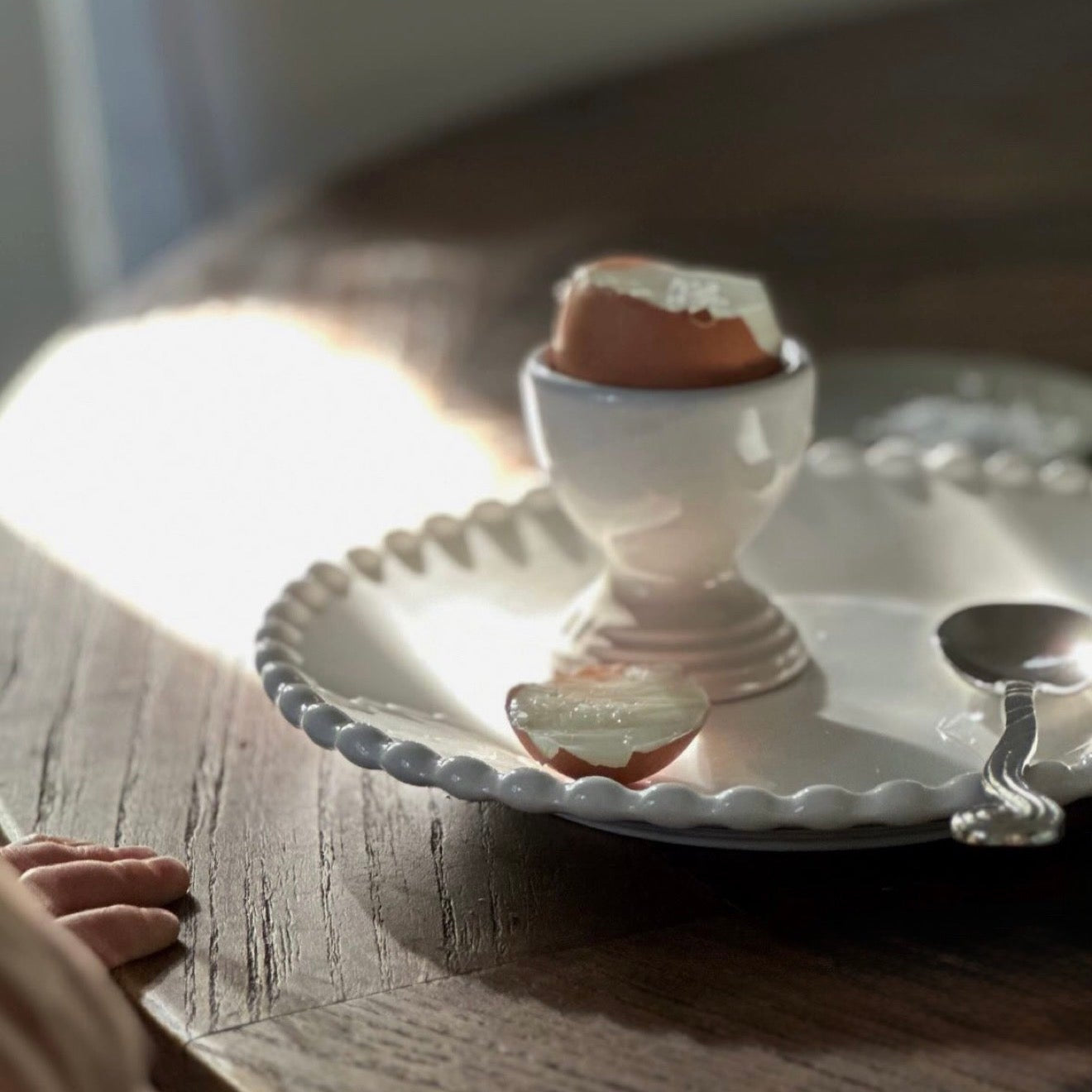 Small white bowl with a piece of bread on a wooden table