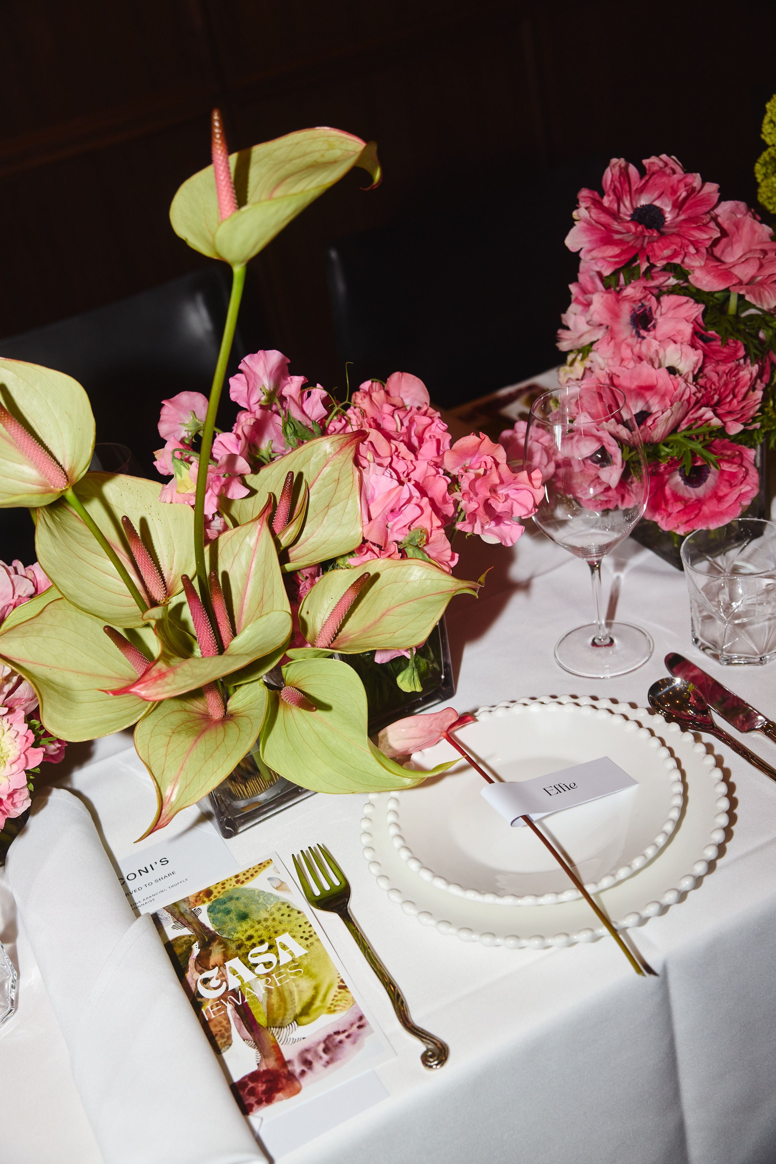 Table setting with floral arrangements and cutlery on a white tablecloth.