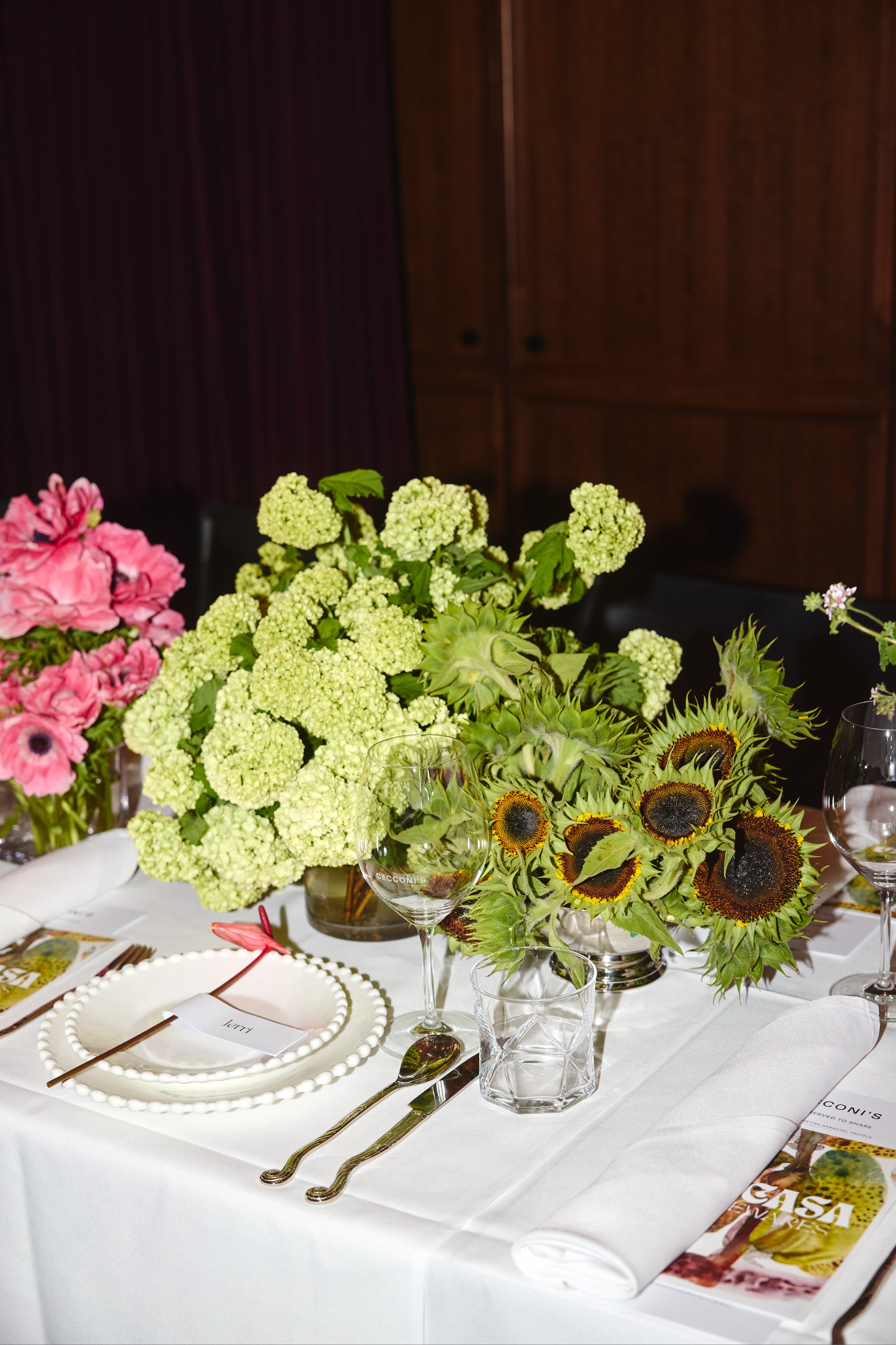 Decorative table setting with flowers, cutlery, and glasses on a white tablecloth.